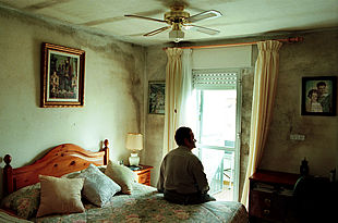 José Romero, en el dormitorio de su casa, afectado por la humedad en paredes y techo.