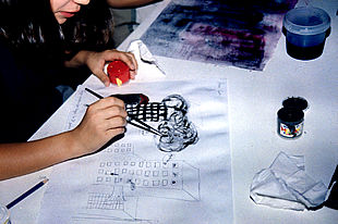 Arriba, una niña dibuja su visión del ataque a las Torres Gemelas.