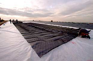 ENVOLVER UNA MONTAÑA EN BASURA. Los operarios de la foto están sellando el antiguo vertedero de Valdemingómez, cerrado en marzo del año pasado. Lo recubren con telas para  encapsular  los 20 millones de toneladas de residuos y obtener el gas metano que almacena esa inmensa montaña de basura, tan grande como el parque del Retiro y con 30 pisos de altura. En 2003, ese lugar se convertirá en 110 hectáreas de zona verde, según las previsiones del Ayuntamiento madrileño. El coste final de la operación alcanzará los 12.000 millones de pesetas.