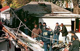 Policías de Nueva York y miembros del FBI investigan entre los restos del fuselaje del avión caídos sobre una casa de Rockaway, en Queens.