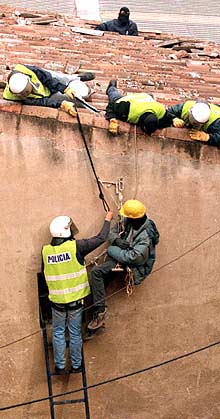 Agentes policiales intentan descolgar a un  okupa. 
