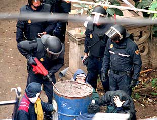 La policía agrieta uno de los bidones con cemento a los que los jóvenes se habían pegado.