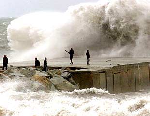 Algunos curiosos se aventuraban ayer en un escollera de Barcelona, azotada por enormes olas.