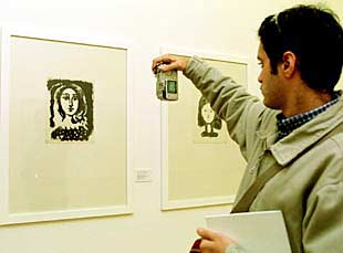 Un visitante de  Picasso from Málaga  fotografía una obra expuesta con una cámara digital.