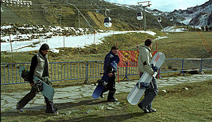 Tres jóvenes con tablas de  snowboard,  en las inmediaciones de la pista del Río, ayer, en Sierra Nevada.
