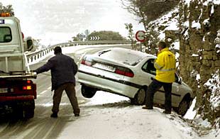 Una grúa retira un vehículo que se salió de la carretera por culpa de la nieve en el Coll d'Ares en Castellón.