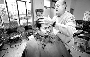 El peluquero de la plaza del Árbol, en el barrio de El Carme, realiza uno de sus últimos cortes.