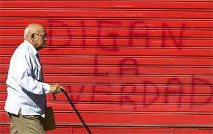 Un hombre pasa junto a un cartel pintado por los manifestantes chavistas en una puerta de  El Nacional. 