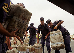 Varios policías manipulan fardos que contienen parte de la cocaína aprehendida en el buque  Tamsaare,  durante la  Operación Temple .