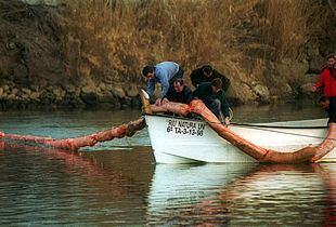 Efectivos de Protección Civil colocan una berrera neumática en el Ebro.