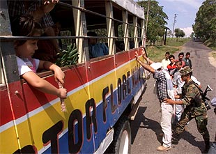 Un soldado registra a un pasajero de un autobús en una carretera que conduce a la zona de distensión.