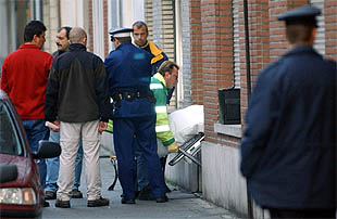 Los servicios forenses levantan el cadáver de una de las víctimas en presencia de la policía.