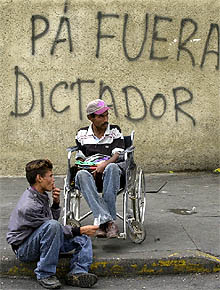 Dos hombres delante de una pintada contra Chávez en el centro de Caracas.
