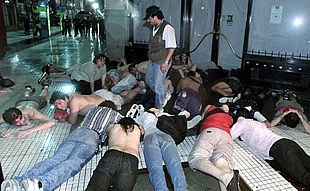 Un policía de paisano vigila a un grupo de detenidos en la protesta de la madrugada del viernes en Buenos Aires.