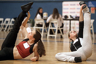 Dos chicas hacen ejercicios de calentamiento antes de participar en la elección de animadora del Real Madrid de baloncesto.