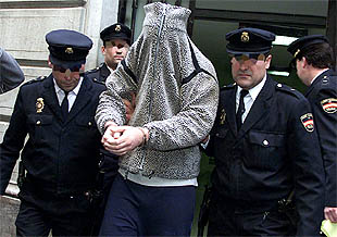 Uno de los detenidos es conducido por la policía a las dependencias judiciales.