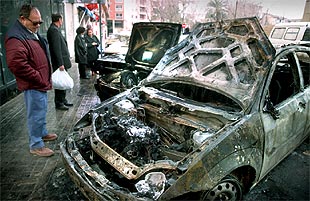 Unos vecinos observan los coches incendiados en la madrugada de ayer en un barrio de Valencia.