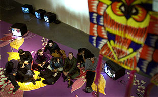 Artistas participantes, con el director del EACC, sentados sobre una de las instalaciones de  Asianvibe. 