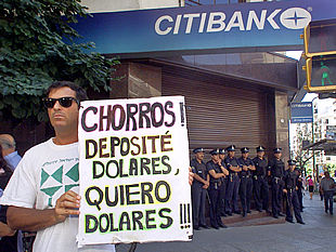 Un argentino exhibe en Buenos Aires un cartel que acusa de 'chorros' (ladrones) a los directivos de los bancos.