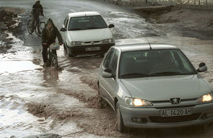 Ciclistas y conductores cruzaban ayer una carretera inundada en Roquetas de Mar.
