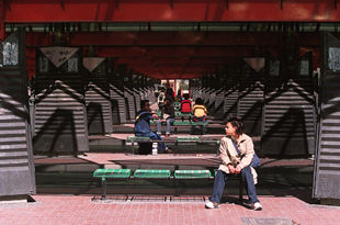 Varios usuarios esperan la llegada de algún autobús en el intercambiador de transportes de la plaza de Castilla.