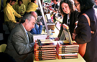 Tomás Eloy Martínez, firmando ejemplares de    El vuelo de la reina. 