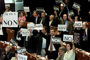 Parlamentarios europeos muestran carteles contra Le Pen durante la intervención del líder ultraderechista.