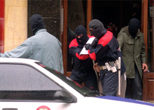 Varios    ertzainas  custodian a un detenido durante un registro efectuado ayer en una vivienda de Vitoria.