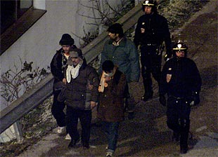 Policías franceses custodian a inmigrantes clandestinos detenidos cerca del túnel del canal de la Mancha.