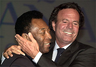 El cantante Julio Iglesias saluda afectuosamente al  cantante Pelé,  ambos embajadores de Unicef, durante el acto celebrado ayer en Sevilla con motivo de la reunión anual del Fondo Mastercard de Ayuda a la Infancia.