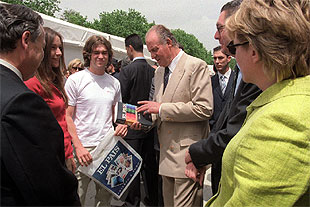 El Rey hojea el    Libro de estilo  de EL PAÍS, durante su recorrido por la Feria del Libro de Madrid, ayer, en el parque del Retiro.