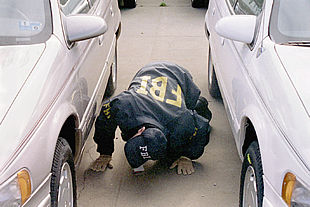 Un agente del FBI revisa los bajos de un automóvil.