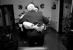 Un enfermo de Alzheimer es ayudado a incorporarse de su sillón.