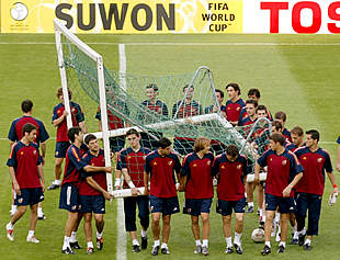 Los jugadores de la selección española, dirigidos por Raúl, colaboran en el traslado de una portería.