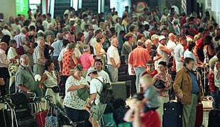 Largas colas de turistas esperan poder embarcar en el aeropuerto de L'Altet