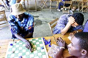  A LA ESPERA DE 'PAPELES'.  Los 423 inmigrantes encerrados en la Universidad Pablo de Olavide de Sevilla abandonaron a medianoche del sábado la huelga de hambre que mantuvieron durante la cumbre europea, pero están decididos a continuar con su protesta hasta lograr  papeles . Para ello cuentan con la mediación del defensor del pueblo andaluz, José Chamizo. En la foto, dos inmigrantes juegan a las damas mientras otro lee.