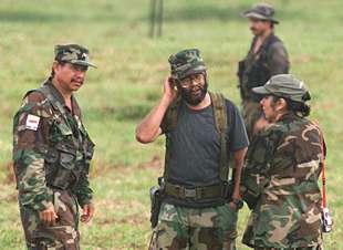 El    comandante  Alfonso Cano (centro) charla con el    comandante  Fabián Martínez y una guerrillera durante las negociaciones de paz en abril de 2000.