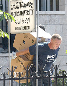 Un israelí se lleva documentación de la universidad palestina Al Quods.