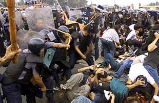 Varios policías se enfrentan a los manifestantes que protestaban, ayer en las calles de Manila, contra la política de la presidenta Gloria Macapagal.