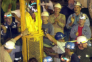 El último  de los mineros es rescatado mientras sus compañeros aplauden.