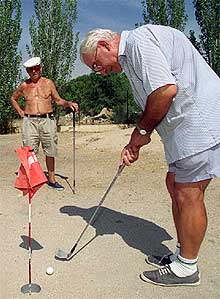 Eusebio Sanz y Cándido Fernández (con camisa) juegan al golf en un terreno del polideportivo de Pan Bendito.