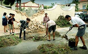 Vecinos de Alginet, ayer, recogiendo los escombros de la pared que un árbol derribó durante la tormenta del miércoles.