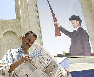 Un iraquí lee el diario   Iraq,   ayer, ante un retrato gigante de Sadam Husein.