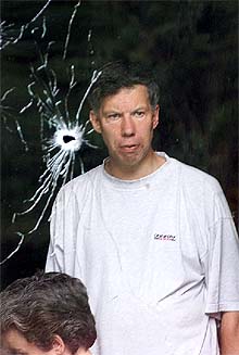 Un profesor de la escuela, tras una ventana agujereada por una bala.