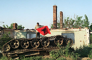 En la aldea de Matejce, un albanés  agita una bandera albanesa sobre los restos de un blindado macedonio destruido en la guerra.