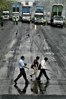 Unos peatones cruzan la Diagonal en medio de las obras de asfaltado, ayer.