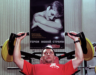Un hombre hace ejercicio bajo un  cartel con la campeona olímpica Svetlana Jórkina y el lema 'El héroe del nuevo país'.