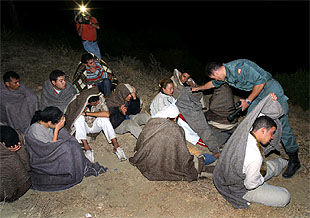 Un guardia civil reparte mantas a un grupo de extranjeros detenidos ayer de madrugada en el Estrecho.