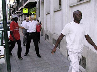 Un policía nacional conduce a la comisaría a dos de los detenidos durante la redada de Murcia.