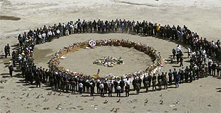Un grupo de familiares de las víctimas del 11-S rodean una ofrenda floral en la ceremonia del aniversario de los atentados, ayer en la  zona cero  de Nueva York.